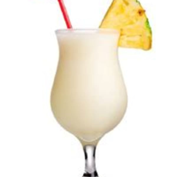 Creamy piña colada in a hurricane glass with a red straw and pineapple wedge garnish.