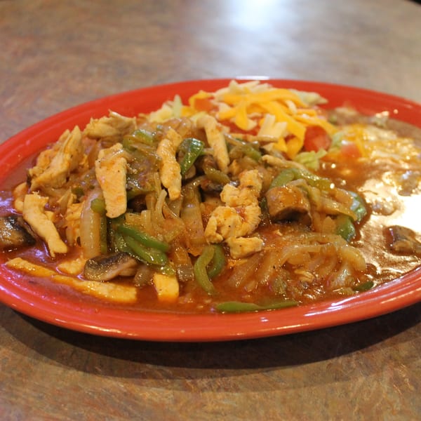 Chicken fajita with onions, green peppers, and mushrooms, served with refried beans and cheese.