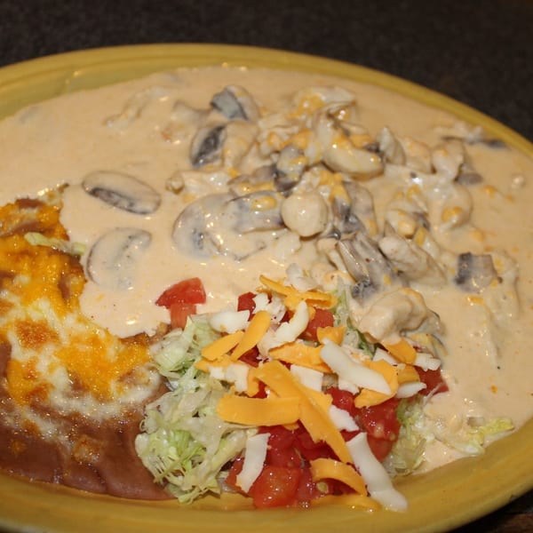 Creamy mushroom dish with refried beans, melted cheese, shredded lettuce, and diced tomatoes.